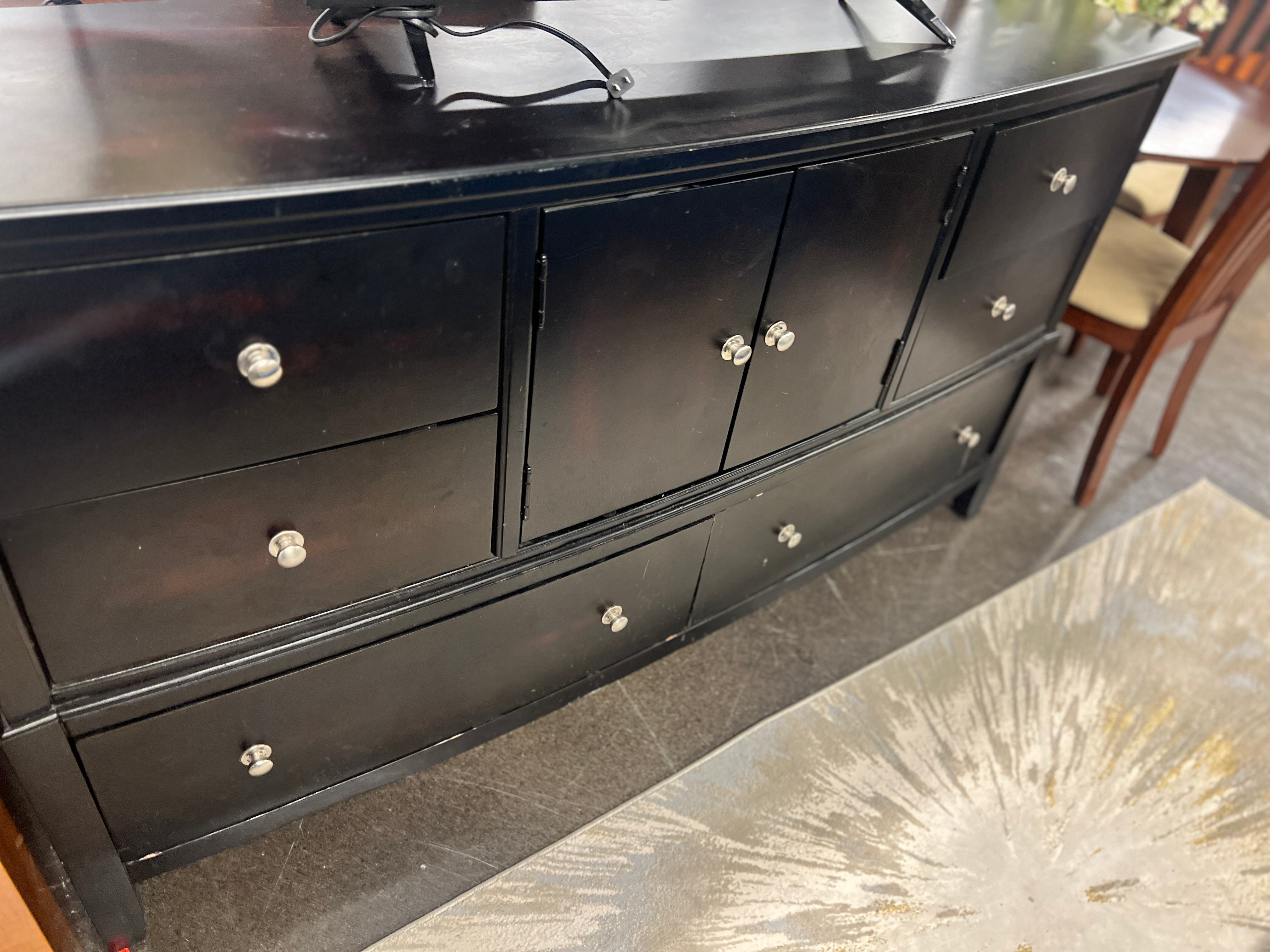 Curved black dresser with silver knobs