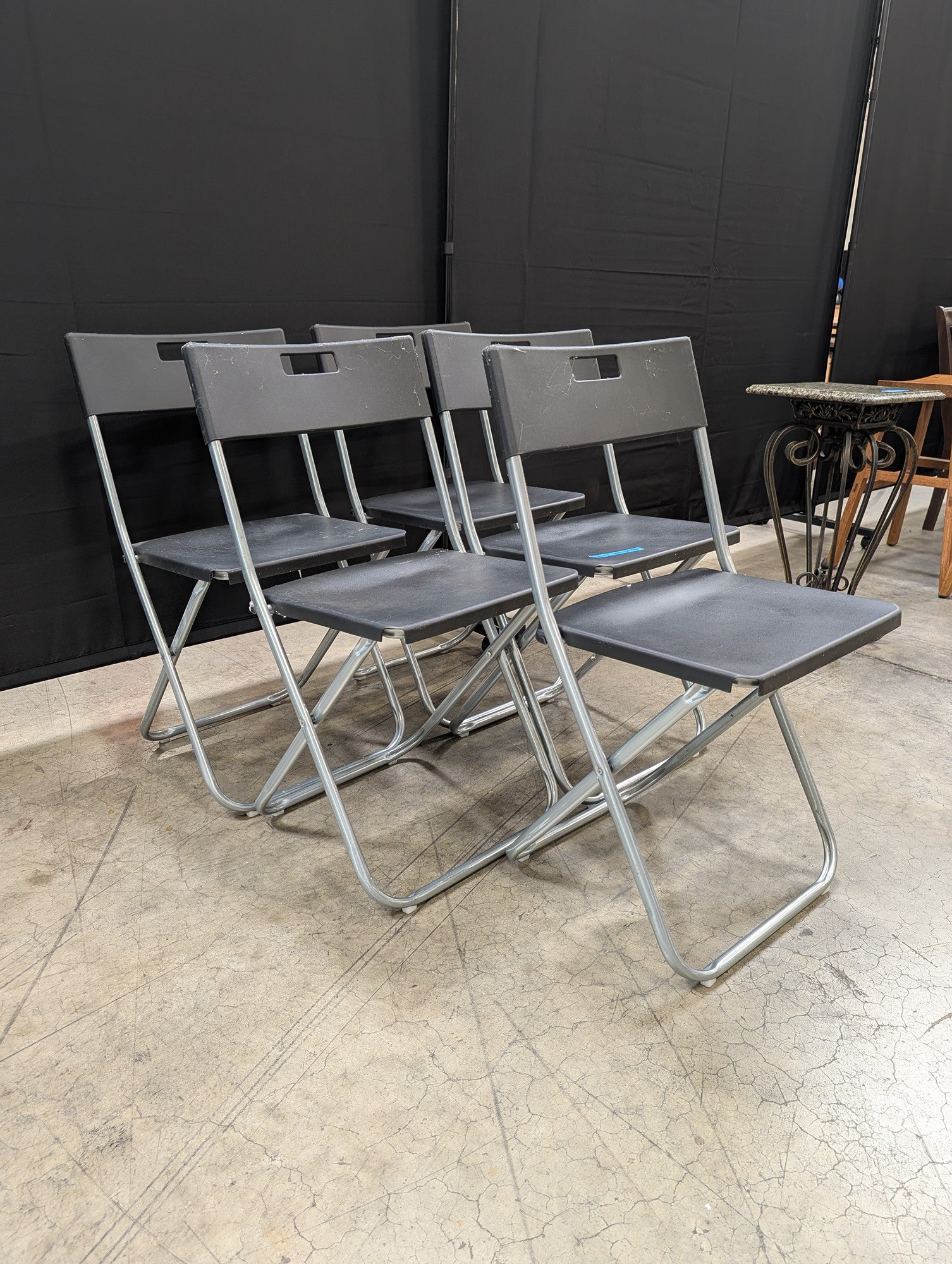 Five Black IKEA Folding Chairs with Cutout Handles
