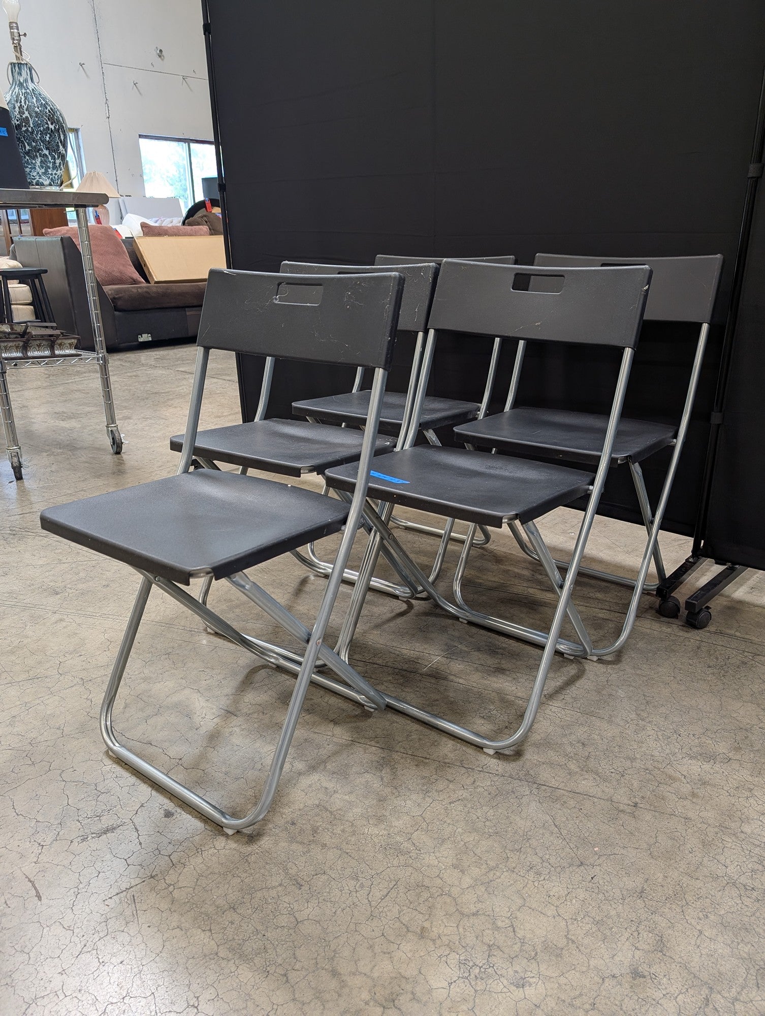 Five Black IKEA Folding Chairs with Cutout Handles