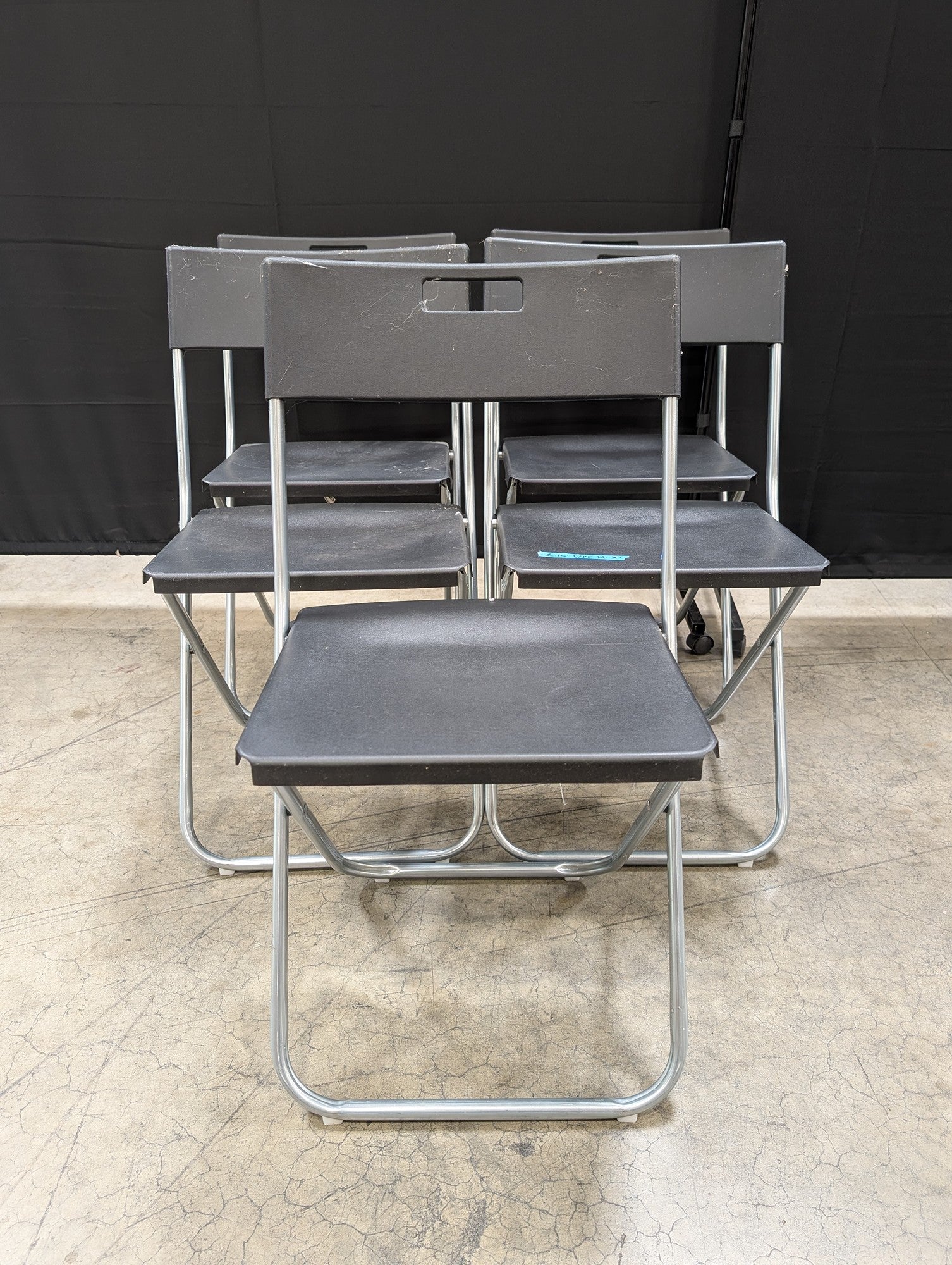 Five Black IKEA Folding Chairs with Cutout Handles