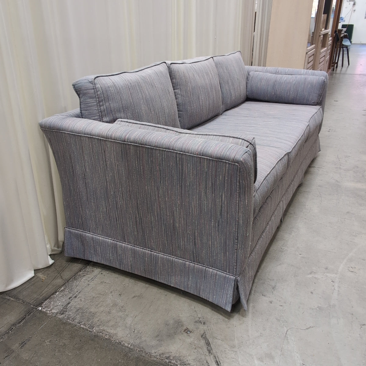 Textured Gray Three-Cushion Couch with Skirted Base