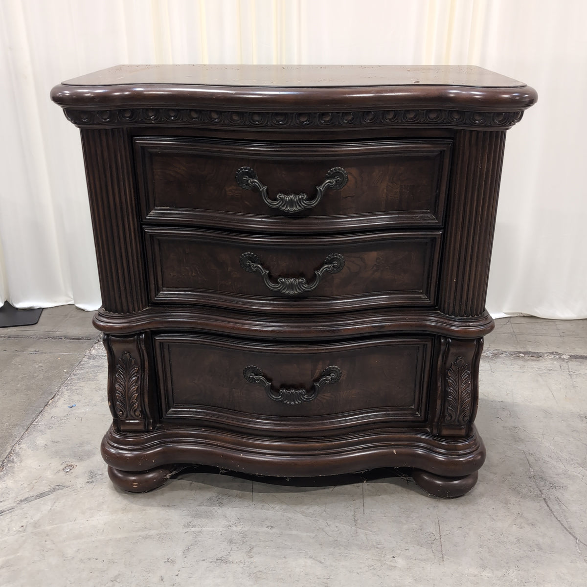 Dark Wood Three-Drawer Nightstand with Ornate Hardware