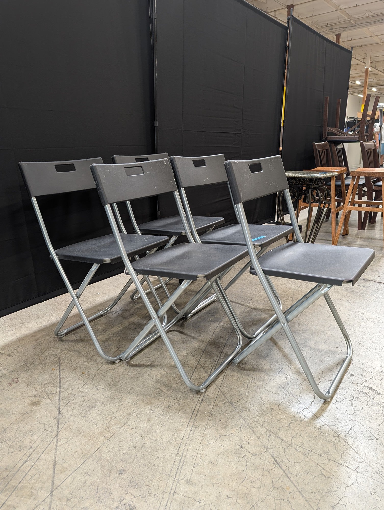 Five Black IKEA Folding Chairs with Cutout Handles