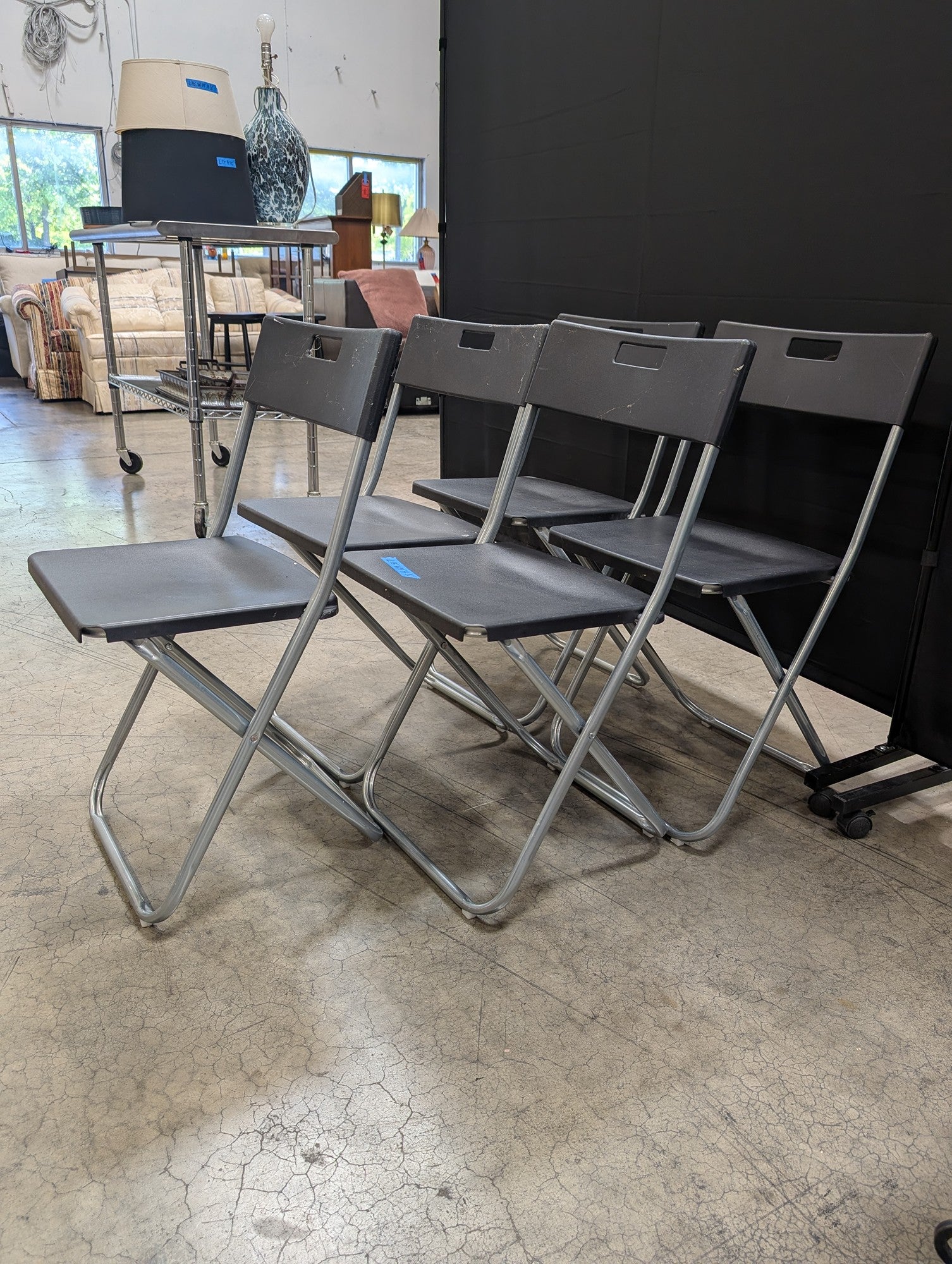 Five Black IKEA Folding Chairs with Cutout Handles
